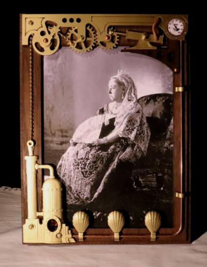 The steampunk Victorian styled mechanical picture frame with gears, pistons, a gauge, boiler and brass chain