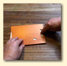 Carefully turn it over and press down the glue or tape through the slot at the bottom